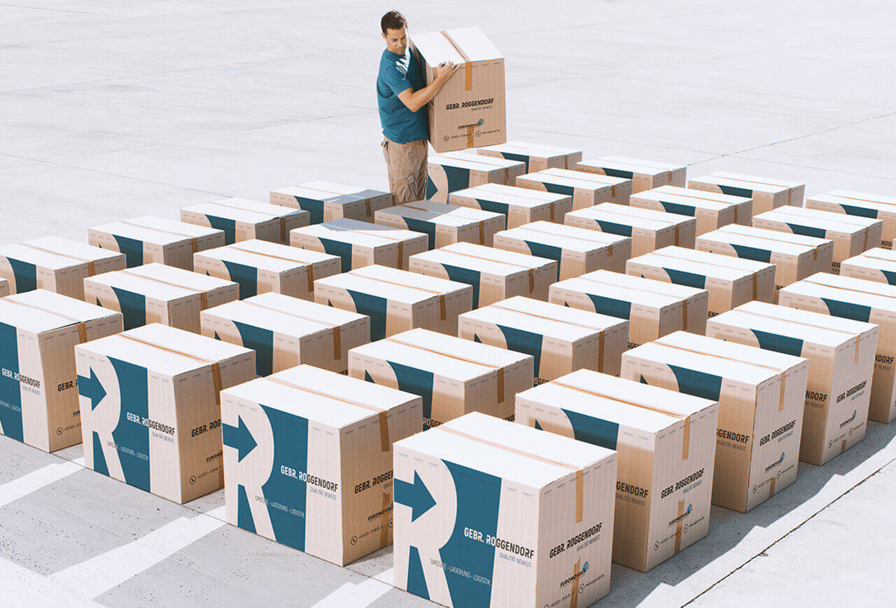 Möbelpacker, der zwischen Umzugskartons steht